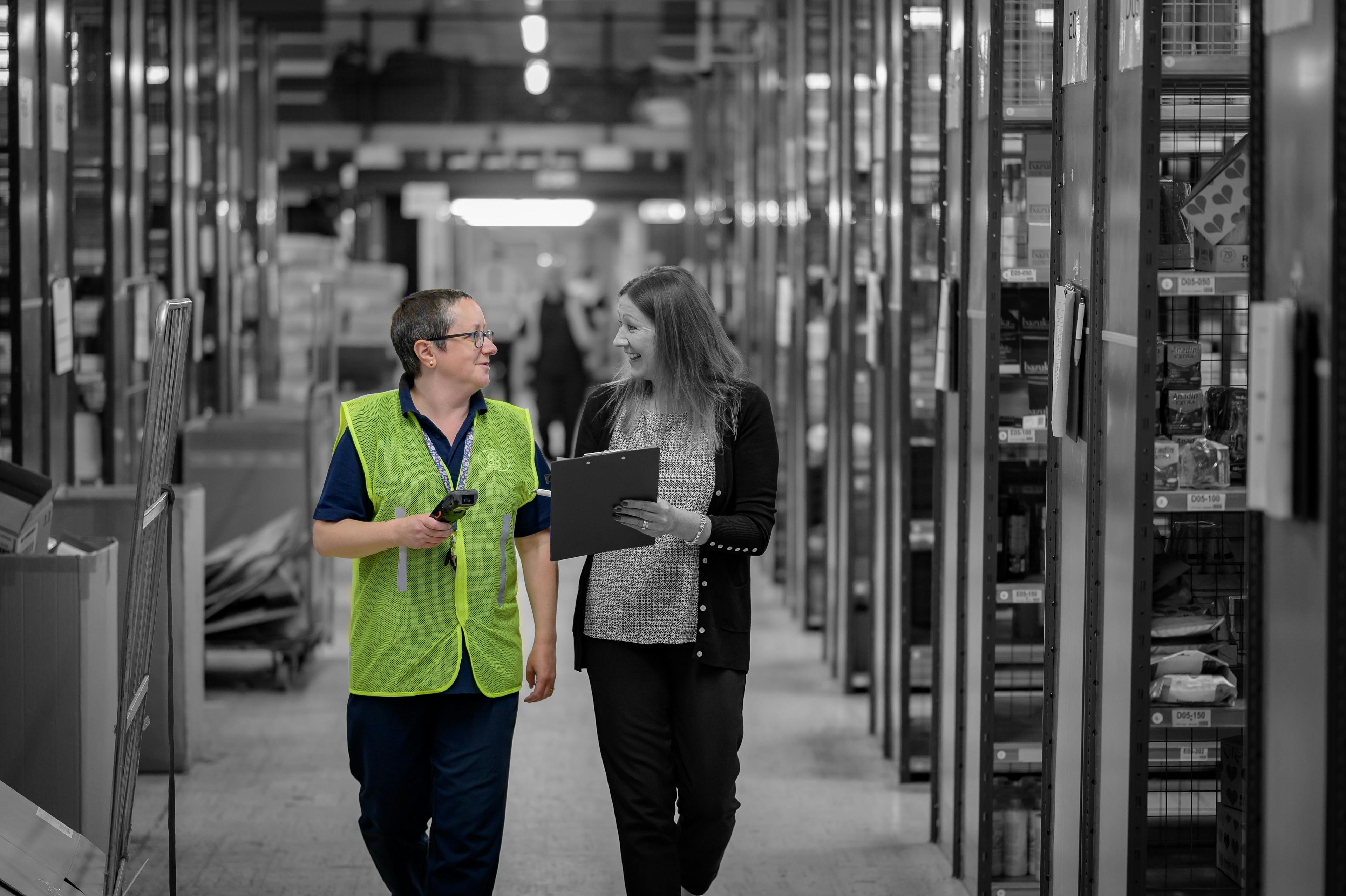 Retail worker talking and smiling with a colleague in a warehouse