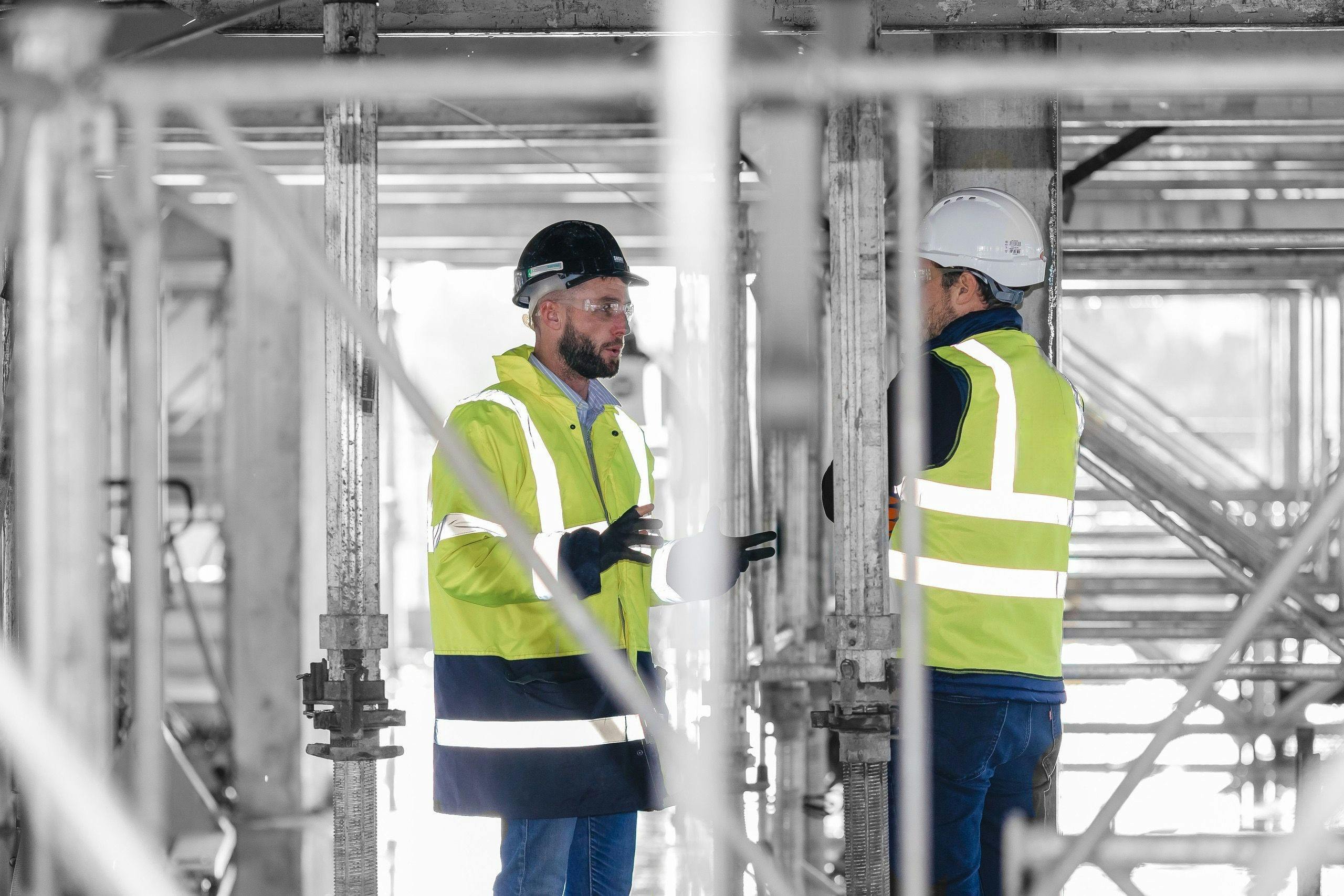 Two construction workers talking in front of scaffolding