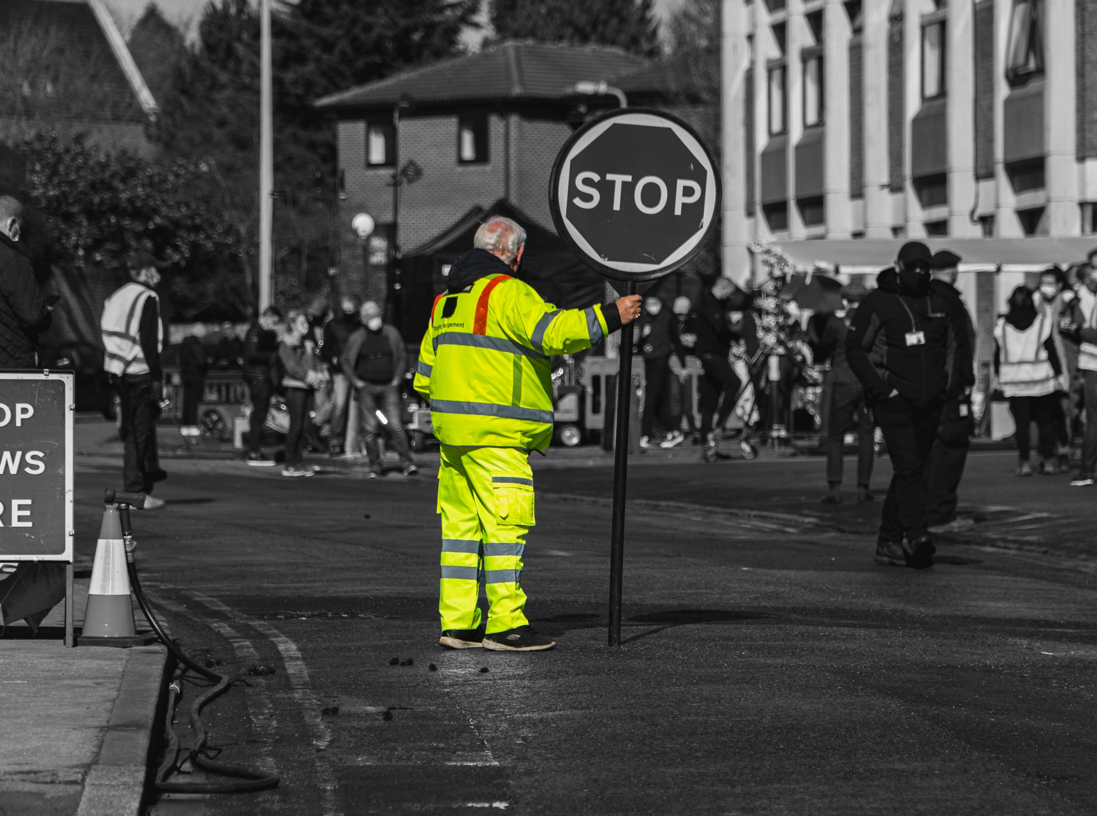 Male worker traffic marshall wearing hi vis clothing with stop sign 