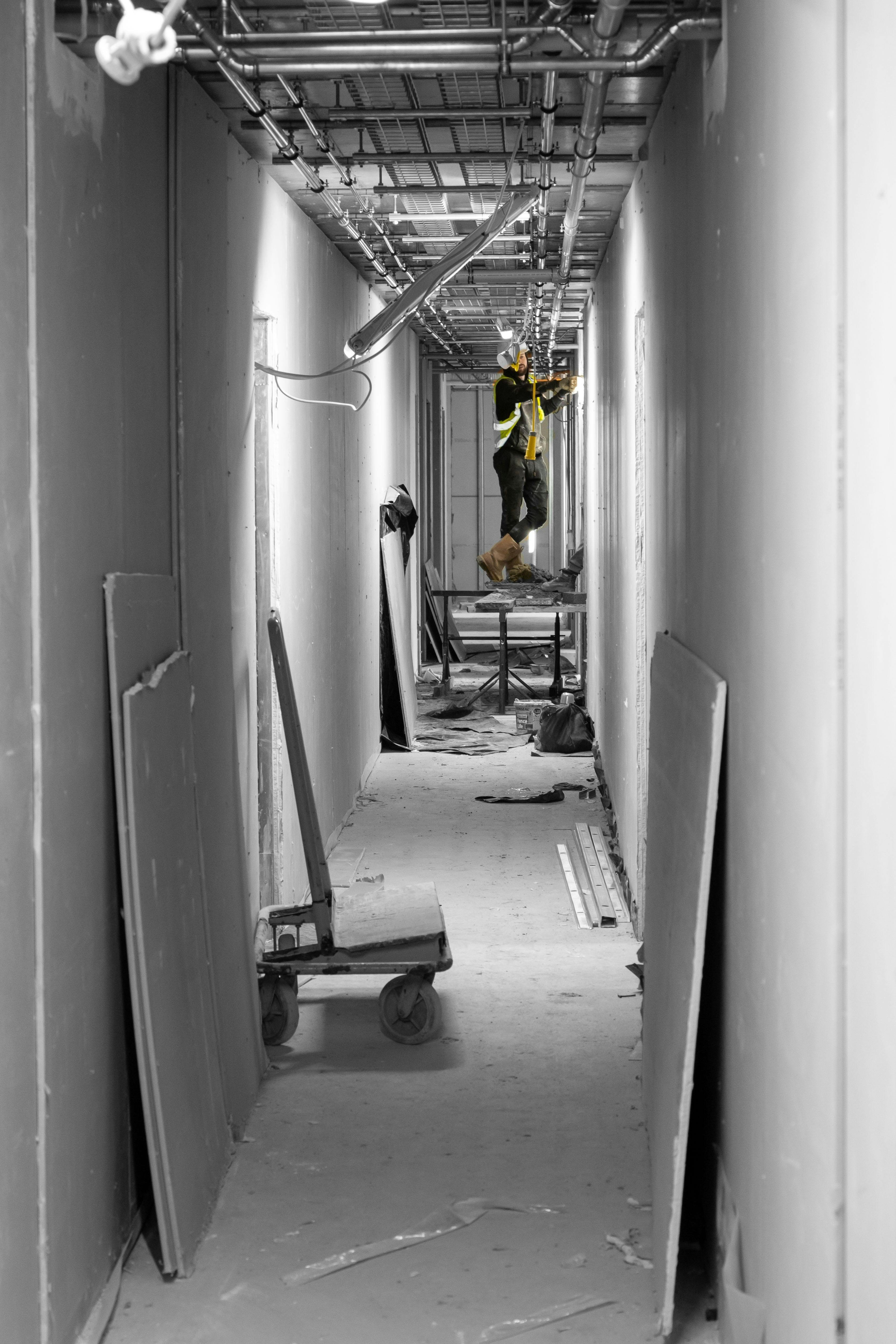 Electrician working on a building site looking at ceiling standing on a ladder